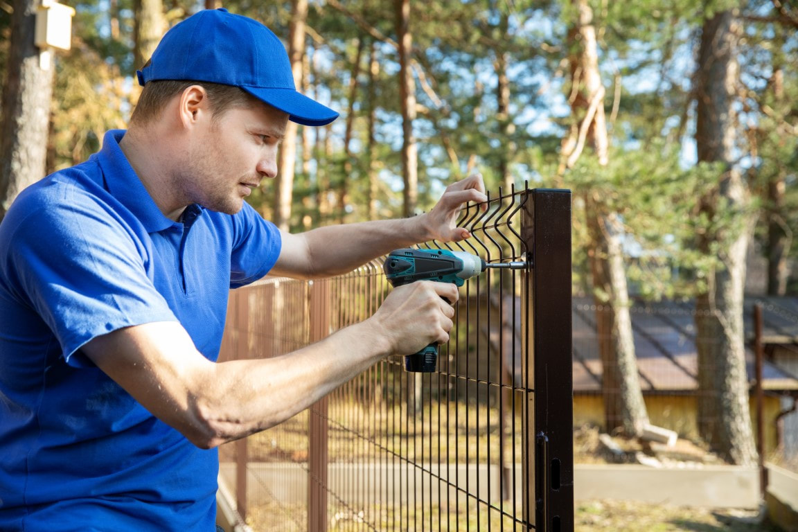 A picture of a man doing fence installation for a fence company