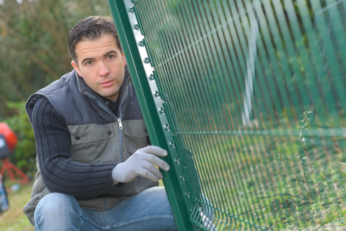 A picture of a man doing fence installation for a fence company