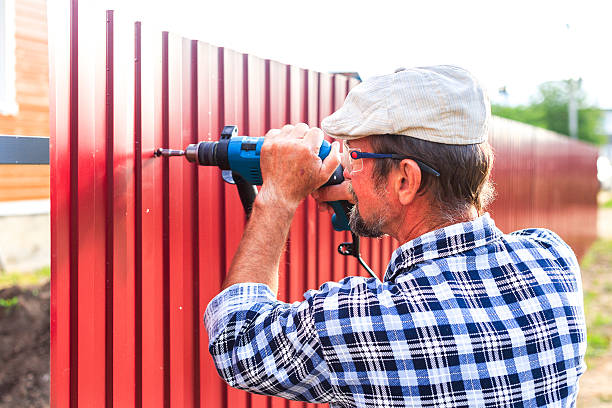 A man using a drill to drill a metal wall
