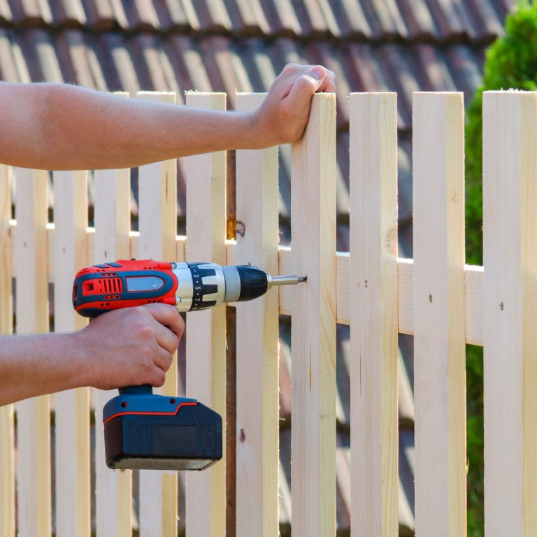 A picture of a person installing a wood fence